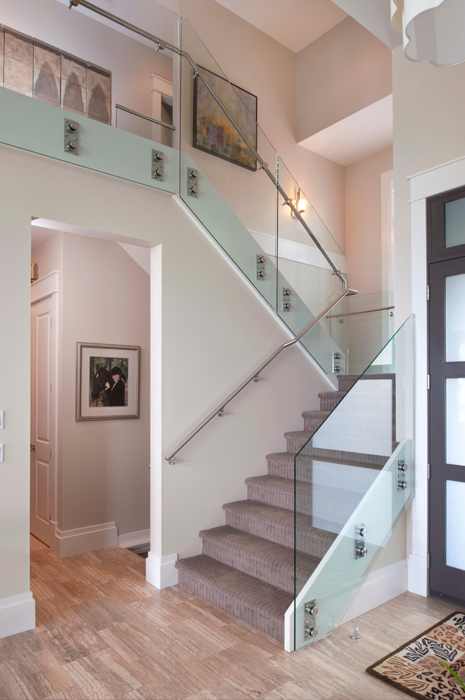 This is an example of a contemporary carpeted u-shaped staircase in Vancouver with carpet risers and glass railing.