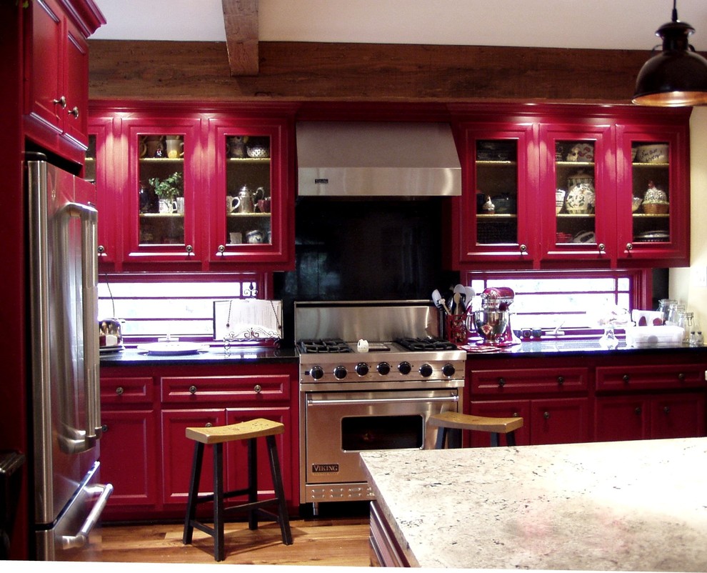 This is an example of a mid-sized country u-shaped open plan kitchen in Houston with a farmhouse sink, glass-front cabinets, red cabinets, marble benchtops, glass sheet splashback, stainless steel appliances and medium hardwood floors.