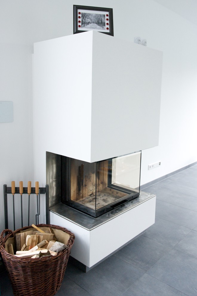 Photo of a large contemporary open concept living room in Dusseldorf with white walls, a wood stove and a plaster fireplace surround.