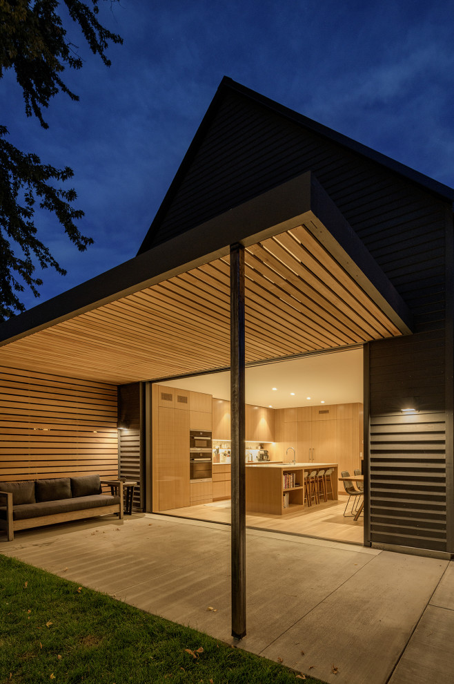 Cette image montre une terrasse arrière minimaliste de taille moyenne avec une dalle de béton et un auvent.