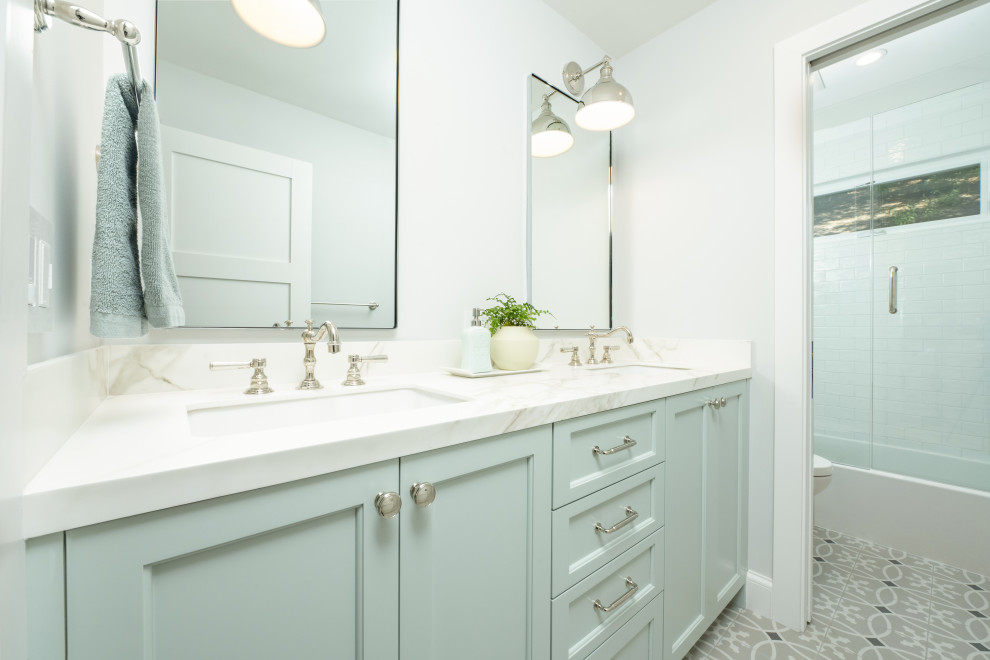 Tub/shower combo - mid-sized transitional kids' white tile and ceramic tile gray floor, double-sink and porcelain tile tub/shower combo idea in San Francisco with shaker cabinets, green cabinets, a one-piece toilet, gray walls, an undermount sink, quartz countertops, a hinged shower door, white countertops and a built-in vanity