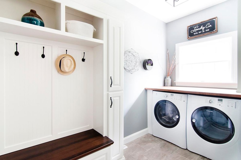 Mid-sized transitional single-wall medium tone wood floor and brown floor utility room photo in Boston with shaker cabinets, white cabinets, wood countertops, blue walls and a side-by-side washer/dryer