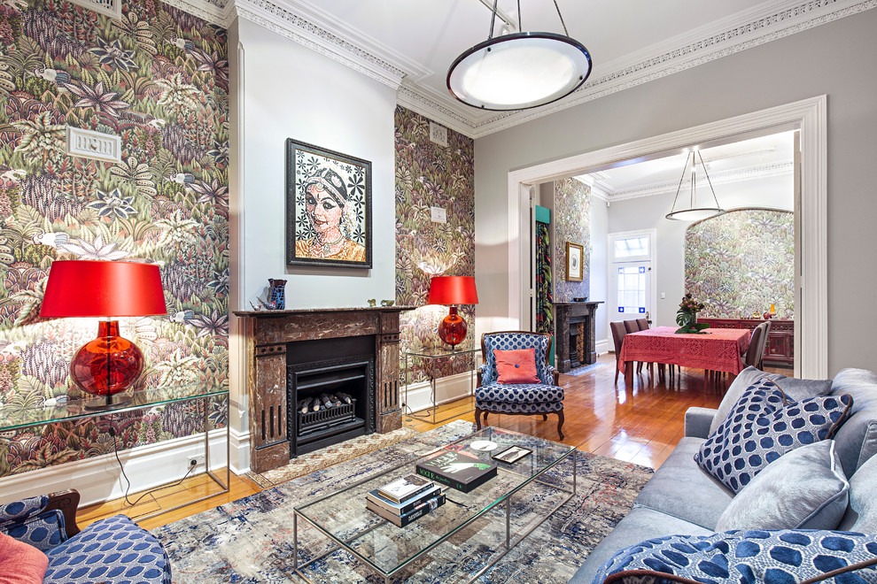 Inspiration for a mid-sized eclectic formal enclosed living room in Sydney with medium hardwood floors, a standard fireplace, brown floor and grey walls.