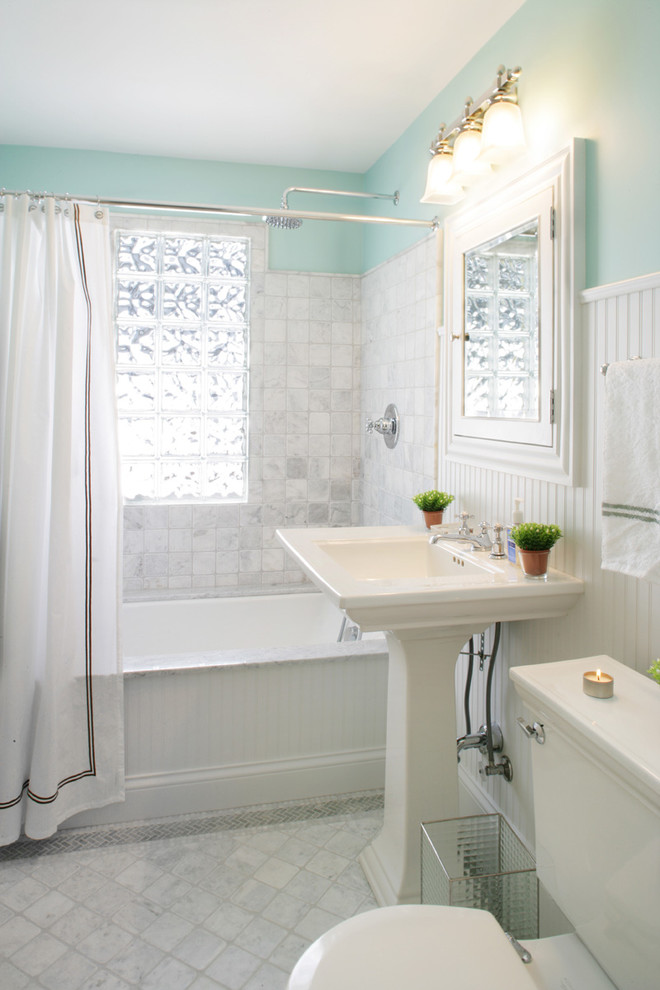 Large traditional kids bathroom in Minneapolis with a pedestal sink, white cabinets, an alcove tub, a shower/bathtub combo, a two-piece toilet, white tile, stone tile, blue walls and marble floors.
