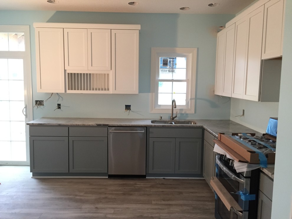 This is an example of a mid-sized beach style l-shaped eat-in kitchen in Other with an undermount sink, shaker cabinets, grey cabinets, granite benchtops, stainless steel appliances, light hardwood floors and with island.