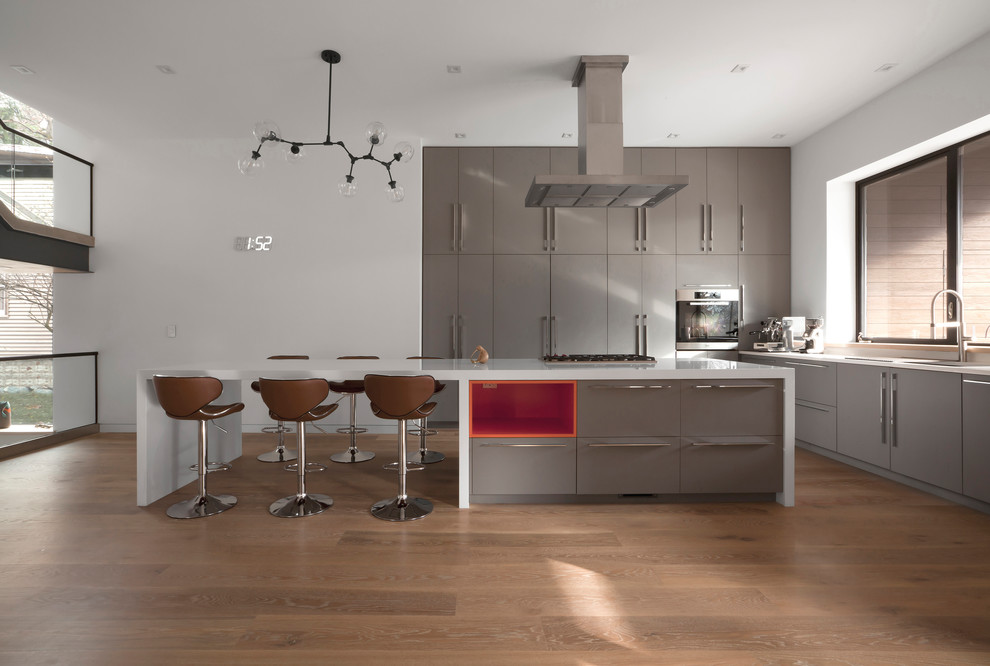 Design ideas for a mid-sized contemporary l-shaped open plan kitchen in Chicago with a single-bowl sink, flat-panel cabinets, grey cabinets, solid surface benchtops, white splashback, window splashback, stainless steel appliances, medium hardwood floors, with island, white benchtop and brown floor.