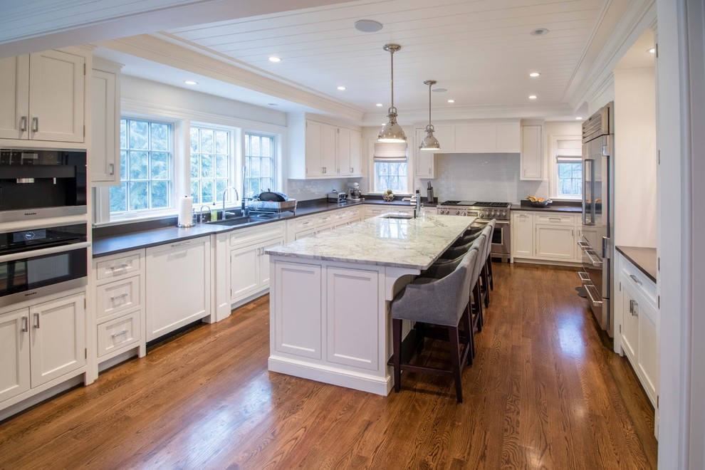 Inspiration for a large transitional eat-in kitchen in Boston with a single-bowl sink, recessed-panel cabinets, white cabinets, quartzite benchtops, white splashback, porcelain splashback, stainless steel appliances, medium hardwood floors and with island.