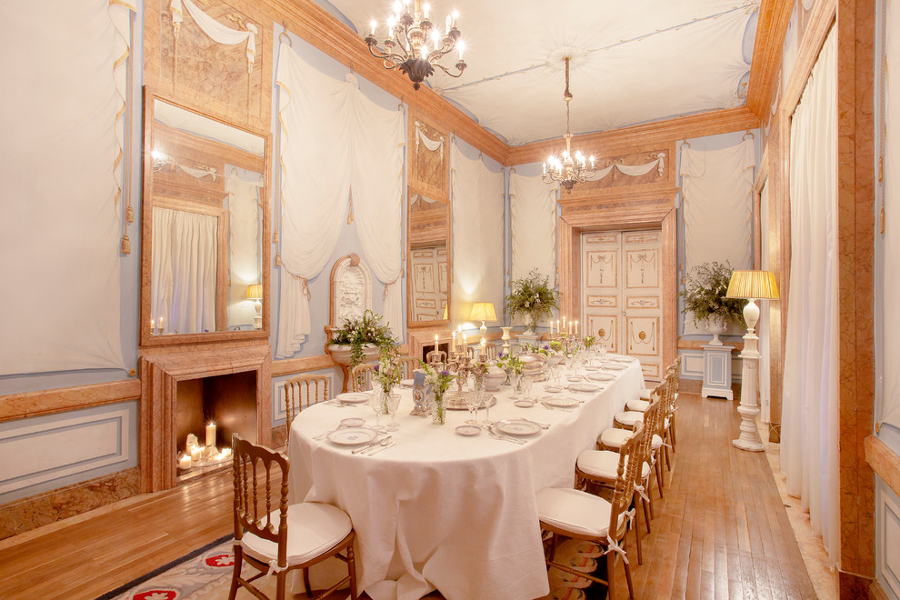 Ejemplo de comedor clásico grande cerrado con paredes multicolor, suelo de madera en tonos medios y todas las chimeneas