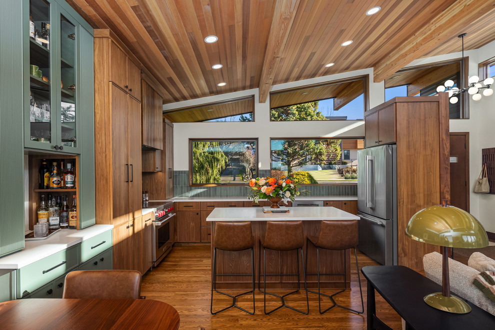 Inspiration for a large 1960s l-shaped medium tone wood floor, brown floor and wood ceiling open concept kitchen remodel in Seattle with an undermount sink, medium tone wood cabinets, quartz countertops, green backsplash, ceramic backsplash, stainless steel appliances, an island and white countertops