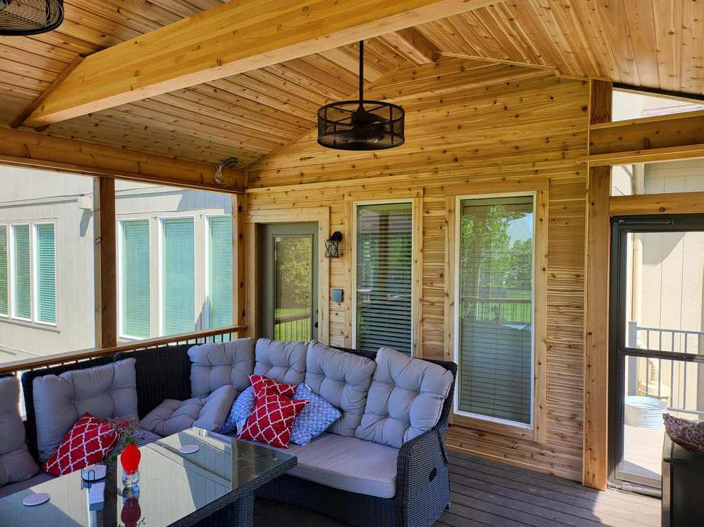 Mid-sized mountain style screened-in and mixed material railing back porch idea in Kansas City with a roof extension