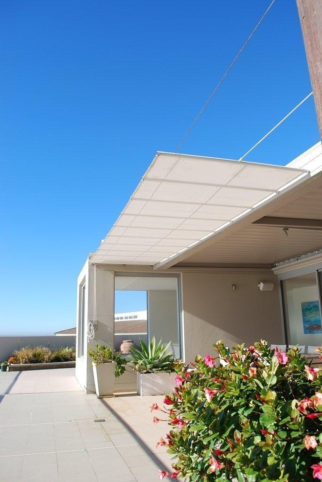 Design ideas for a beach style courtyard patio in Sydney with tile and an awning.