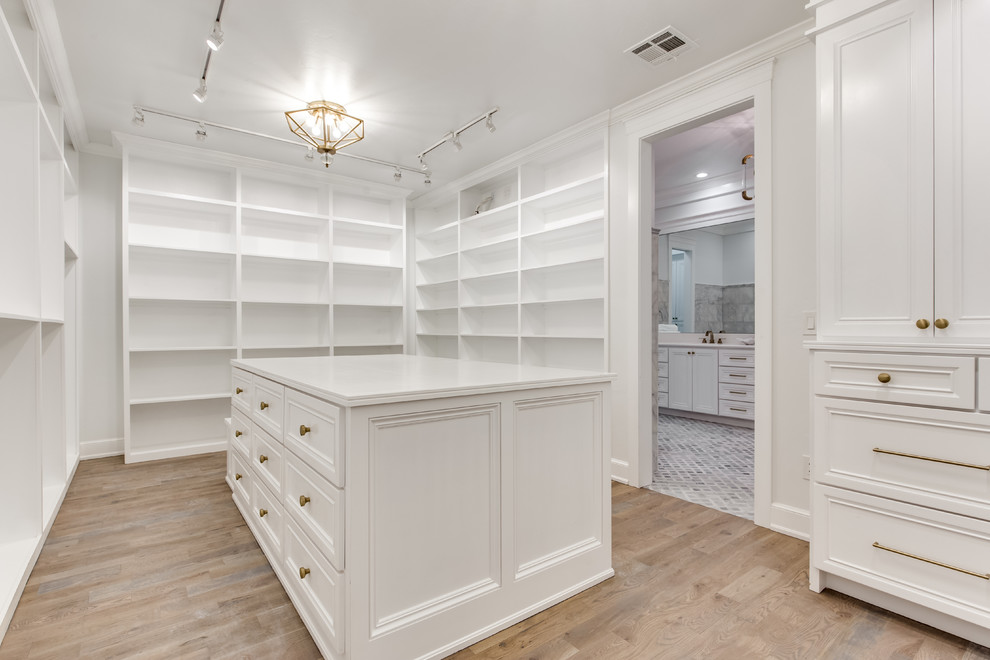 This is an example of an expansive transitional gender-neutral walk-in wardrobe in Oklahoma City with recessed-panel cabinets, white cabinets and medium hardwood floors.