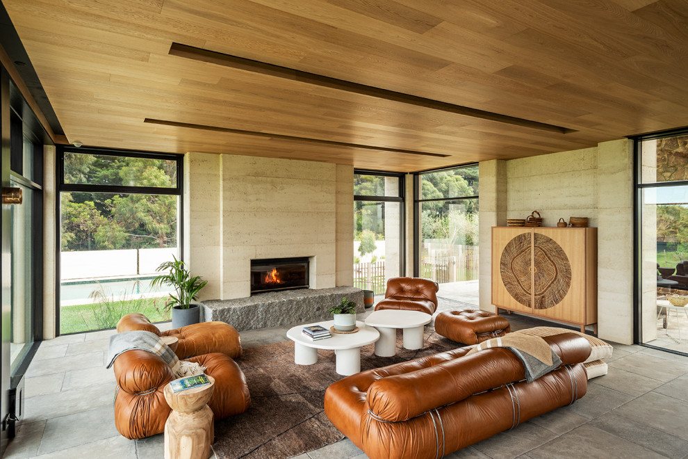 This is an example of a large contemporary open concept living room in Melbourne with beige walls, a standard fireplace, a stone fireplace surround, a concealed tv, grey floor and wood.