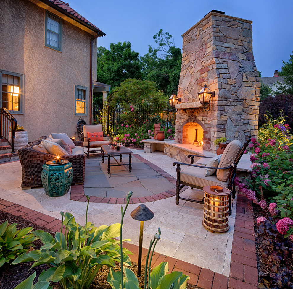 This is an example of a mid-sized mediterranean side yard patio in Minneapolis with no cover, natural stone pavers and with fireplace.