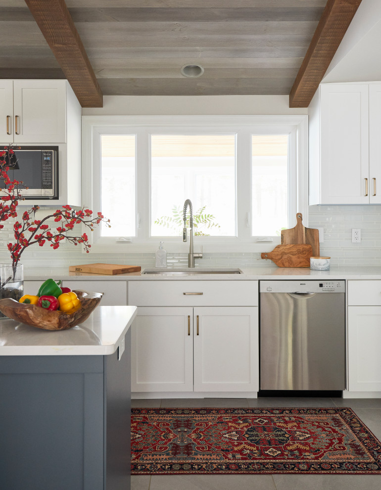 Mid-sized transitional u-shaped ceramic tile, gray floor and vaulted ceiling eat-in kitchen photo with an undermount sink, shaker cabinets, white cabinets, quartz countertops, white backsplash, glass tile backsplash, stainless steel appliances, an island and white countertops