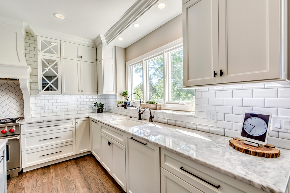 Photo of a transitional open plan kitchen in Chicago with white splashback, subway tile splashback and multiple islands.