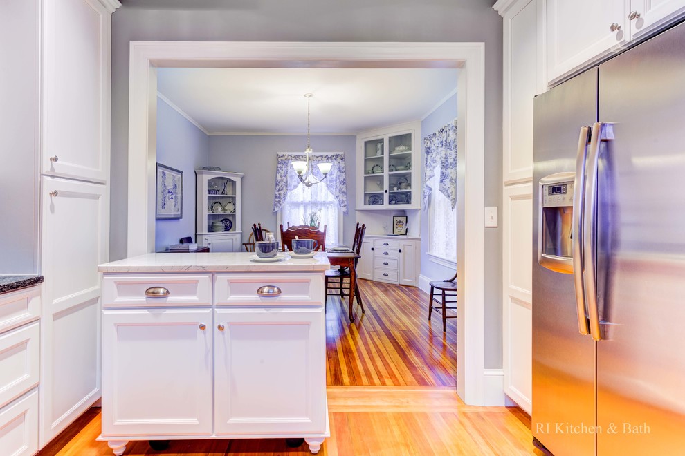 Inspiration for a large transitional u-shaped medium tone wood floor eat-in kitchen remodel in Providence with an undermount sink, shaker cabinets, white cabinets, granite countertops, blue backsplash, stone tile backsplash, stainless steel appliances and an island