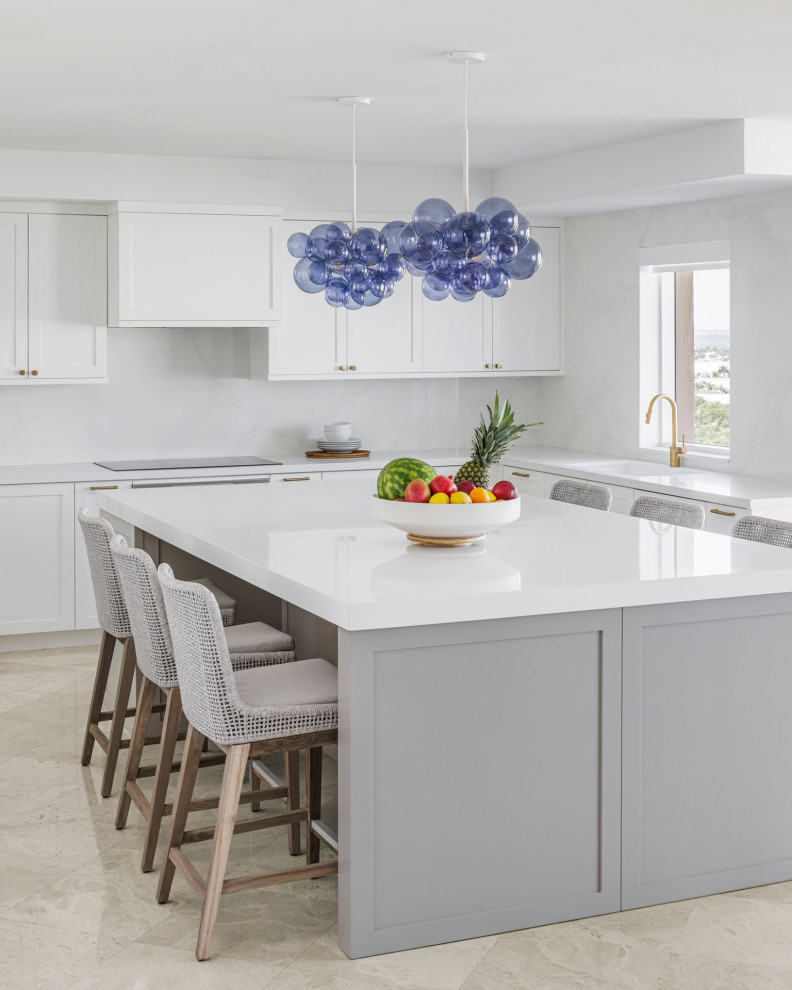 Large coastal l-shaped kitchen in Miami with white cabinets, white splashback, an island, white worktops, a single-bowl sink, shaker cabinets and beige floors.