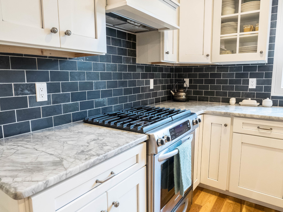 Kitchen - mid-sized transitional medium tone wood floor kitchen idea in New York with shaker cabinets, white cabinets, marble countertops, blue backsplash, subway tile backsplash and stainless steel appliances