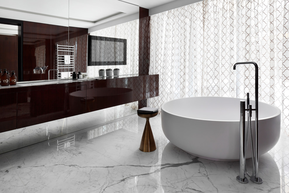 Photo of a large contemporary master bathroom in London with flat-panel cabinets, dark wood cabinets, a freestanding tub, a curbless shower, a bidet, white walls, marble floors, a wall-mount sink and wood benchtops.