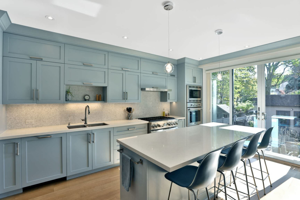 Design ideas for a mid-sized contemporary u-shaped separate kitchen in DC Metro with an undermount sink, shaker cabinets, blue cabinets, quartz benchtops, white splashback, mosaic tile splashback, stainless steel appliances, medium hardwood floors, with island, yellow floor and white benchtop.