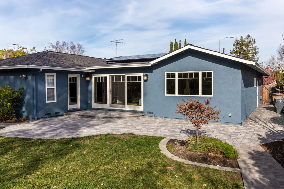 Cette image montre une petite façade de maison bleue vintage en stuc de plain-pied avec un toit à deux pans, un toit en shingle et un toit noir.