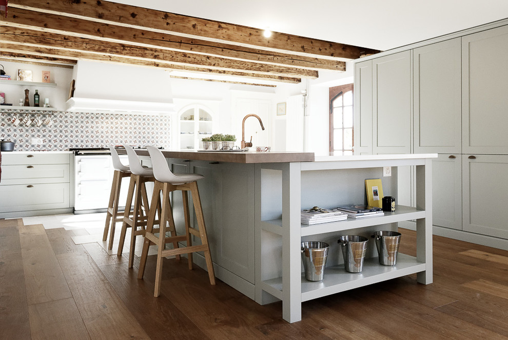 Aménagement de cuisine américaine in L With un évier encastré, un placard à porte shaker, des portes de placard grises, un plan de travail en quartz modifié, une crédence multicolore, une crédence en carreau de ciment, un électroménager de couleur, un sol en bois brun, îlot, un sol beige and un plan de travail blanc.