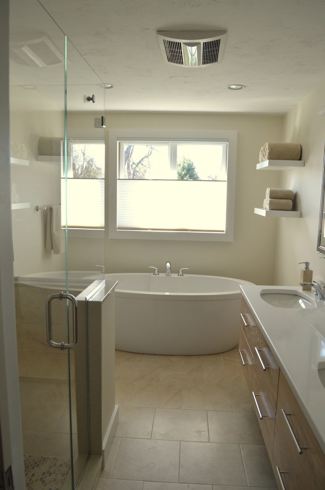 This is an example of a large contemporary master bathroom in Boston with light wood cabinets, a freestanding tub, a corner shower, beige tile, an undermount sink, flat-panel cabinets, a wall-mount toilet, porcelain tile, porcelain floors and engineered quartz benchtops.