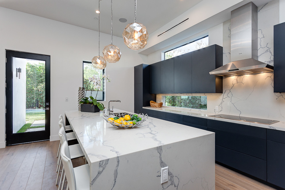 Design ideas for a large modern l-shaped open plan kitchen in Los Angeles with an undermount sink, flat-panel cabinets, black cabinets, marble benchtops, white splashback, stone slab splashback, stainless steel appliances, vinyl floors and with island.