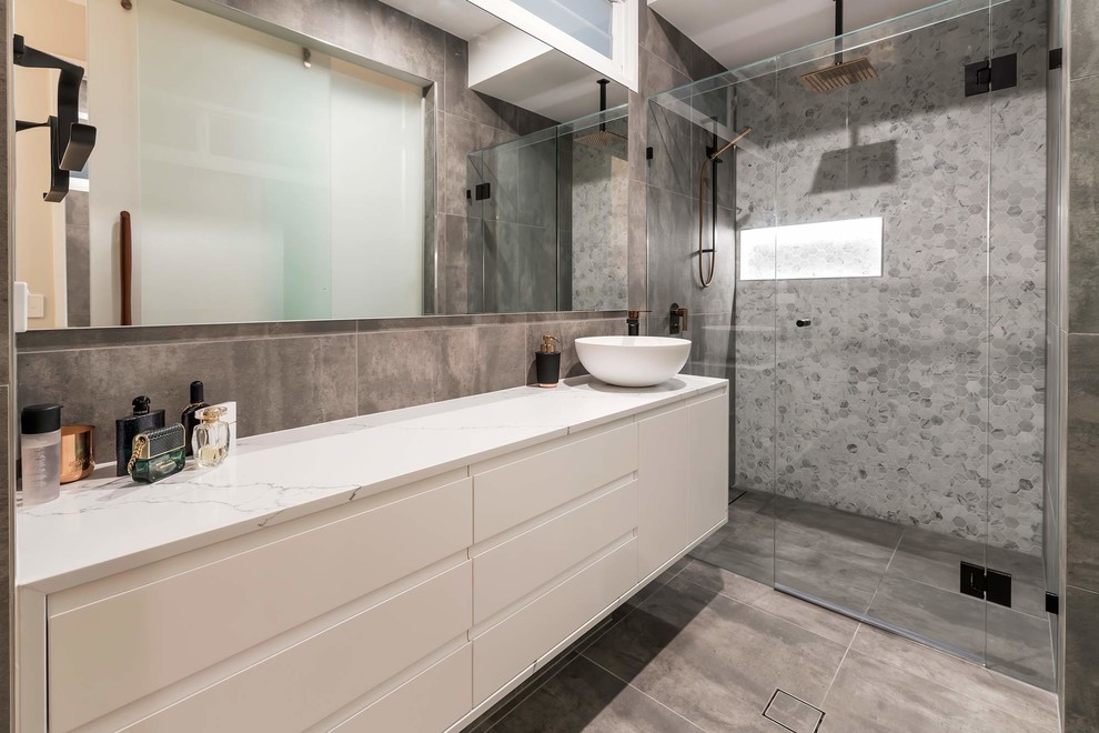 Design ideas for a mid-sized modern wet room bathroom in Gold Coast - Tweed with flat-panel cabinets, white cabinets, gray tile, porcelain tile, grey walls, porcelain floors, a vessel sink, marble benchtops, a hinged shower door and white benchtops.