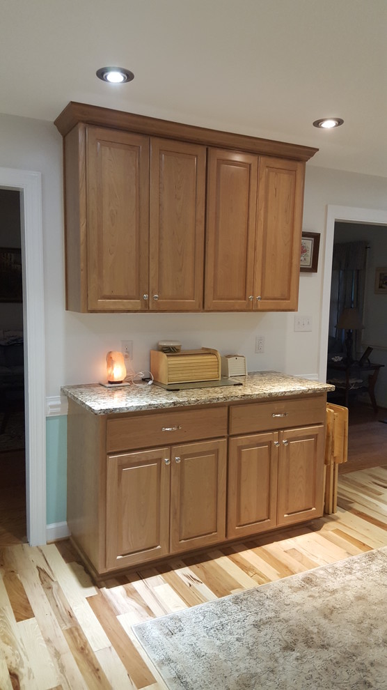 Inspiration for a small transitional u-shaped medium tone wood floor eat-in kitchen remodel with an undermount sink, raised-panel cabinets, medium tone wood cabinets, granite countertops, stainless steel appliances and no island