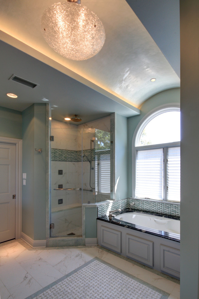 Photo of a large contemporary master bathroom in Austin with raised-panel cabinets, white cabinets, granite benchtops, an undermount tub, white tile, stone tile, blue walls and porcelain floors.
