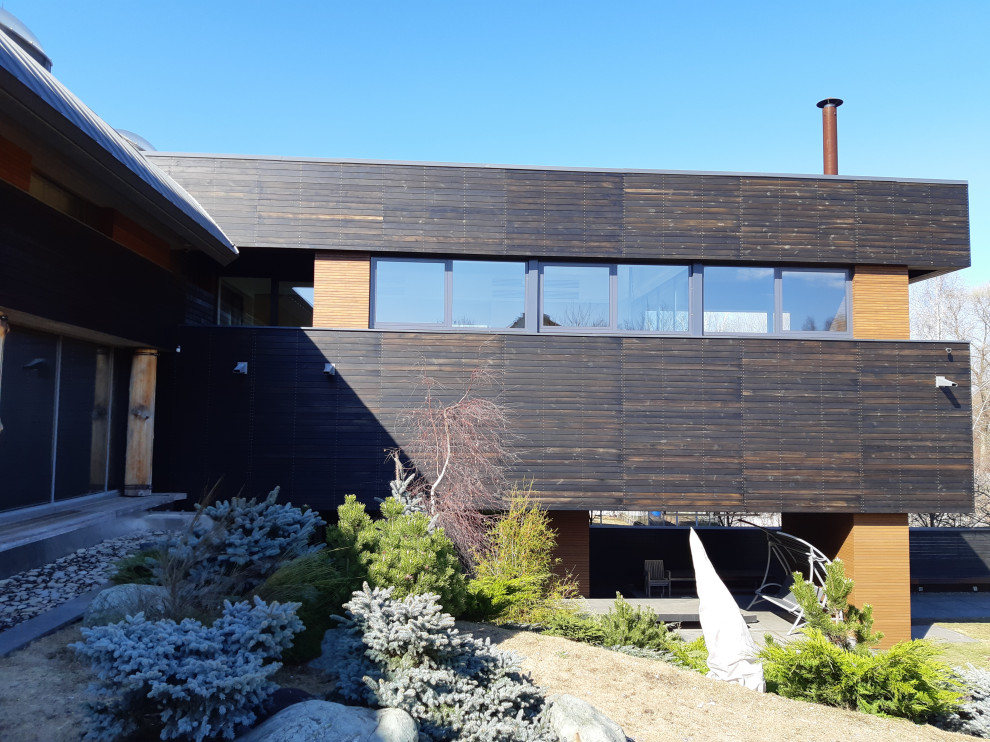 Свежая идея для дизайна: большой, деревянный, черный дом в современном стиле с разными уровнями, металлической крышей, серой крышей и отделкой планкеном - отличное фото интерьера