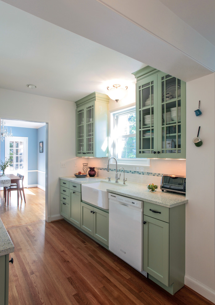 Design ideas for a small traditional galley separate kitchen in DC Metro with a farmhouse sink, recessed-panel cabinets, green cabinets, quartz benchtops, white splashback, ceramic splashback, white appliances, medium hardwood floors and no island.