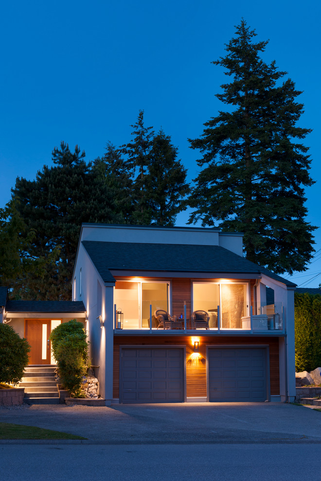 This is an example of a mid-sized transitional split-level stucco grey exterior in Vancouver.