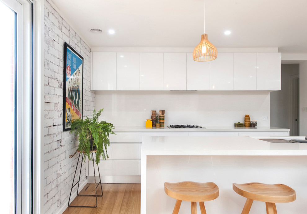 This is an example of a small midcentury galley open plan kitchen in Canberra - Queanbeyan with an undermount sink, beaded inset cabinets, white cabinets, quartz benchtops, white splashback, stone slab splashback, stainless steel appliances, light hardwood floors and with island.
