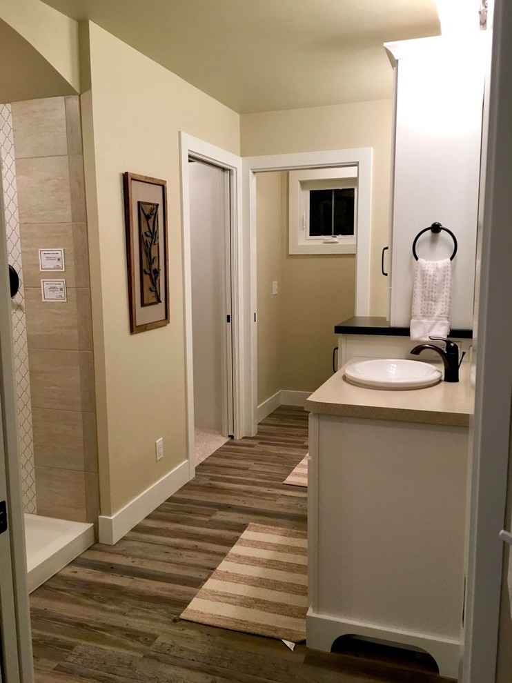 Mid-sized traditional 3/4 bathroom in Other with recessed-panel cabinets, white cabinets, a corner shower, beige tile, beige walls, light hardwood floors, a pedestal sink and limestone benchtops.