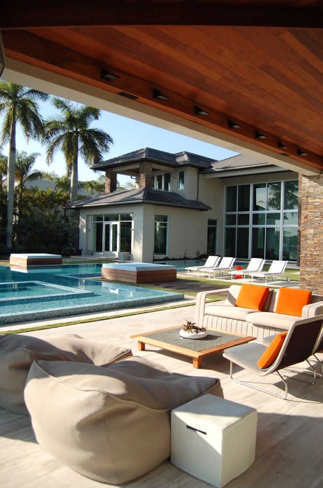 This is an example of a large contemporary courtyard custom-shaped lap pool in Miami with a pool house and tile.