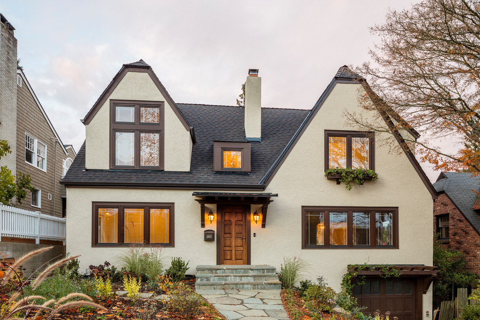 Photo of a traditional two-storey stucco beige house exterior in Seattle with a gable roof and a shingle roof.