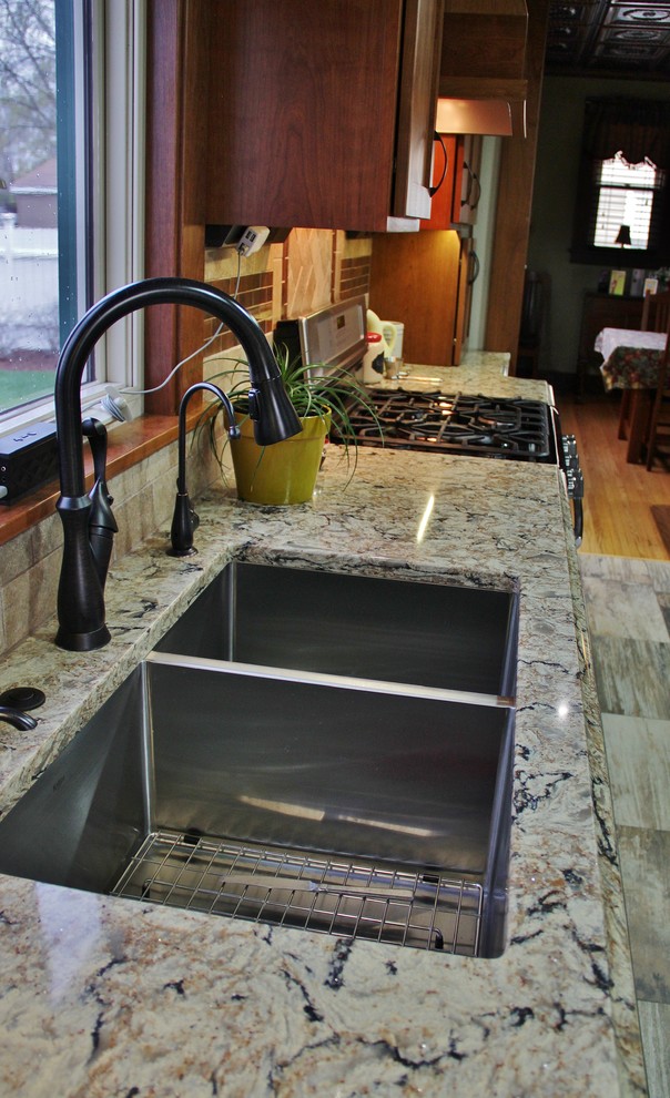 Mid-sized transitional galley ceramic tile enclosed kitchen photo with an undermount sink, shaker cabinets, medium tone wood cabinets, quartz countertops, beige backsplash, stone tile backsplash, stainless steel appliances and a peninsula