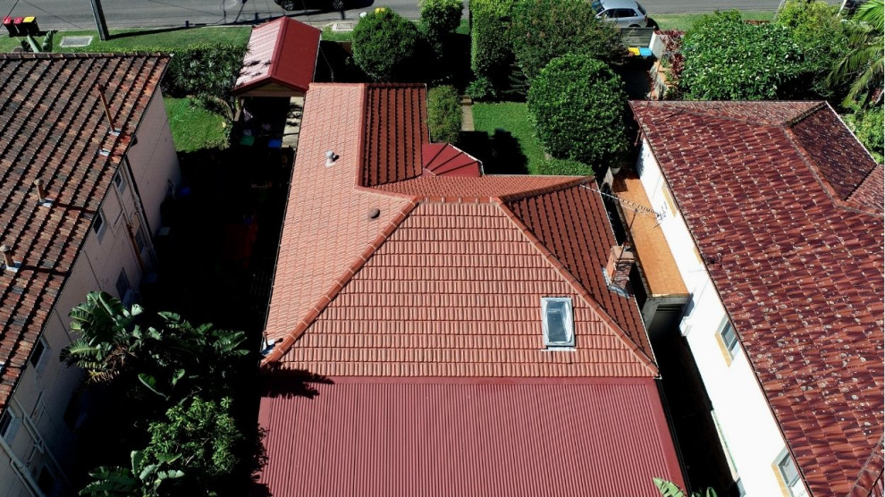 Immagine della facciata di una casa classica con tetto a padiglione, copertura mista e tetto rosso