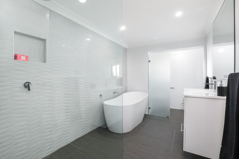 This is an example of a mid-sized contemporary bathroom in Sydney with flat-panel cabinets, white cabinets, a freestanding tub, an open shower, white tile, ceramic tile, white walls, porcelain floors, engineered quartz benchtops, grey floor and white benchtops.