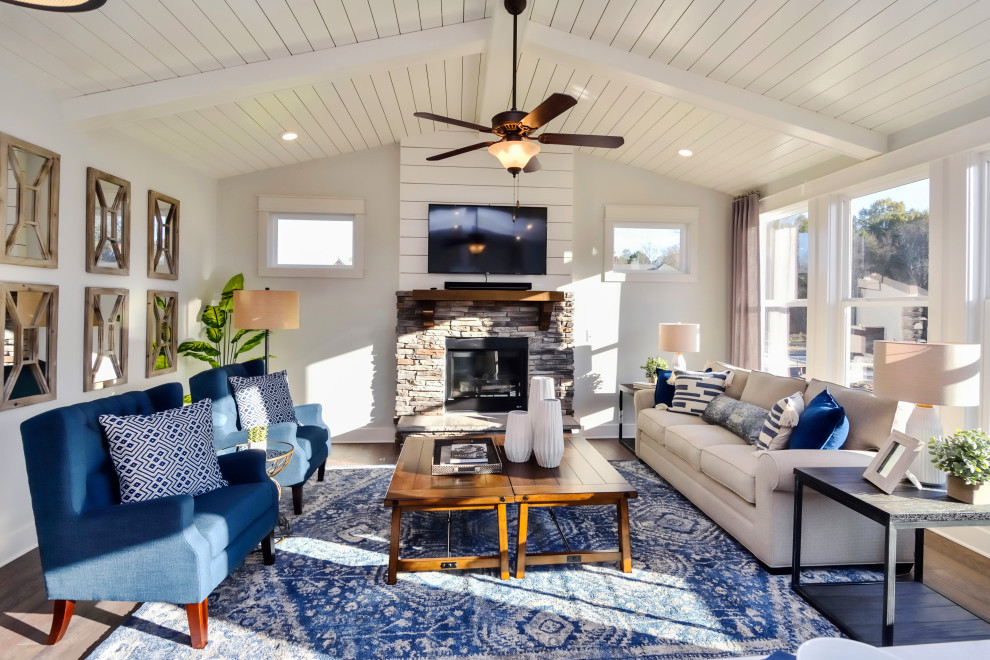 This is an example of a farmhouse living room in Nashville with white walls, dark hardwood flooring, a standard fireplace, a stacked stone fireplace surround, brown floors, exposed beams, a timber clad ceiling and a vaulted ceiling.