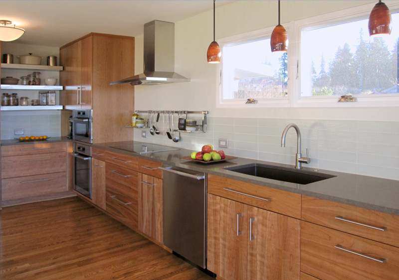 Contemporary open plan kitchen in Seattle with an undermount sink, medium wood cabinets, solid surface benchtops, yellow splashback, glass tile splashback, stainless steel appliances and medium hardwood floors.