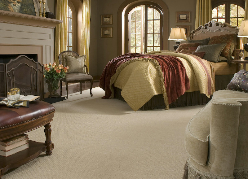 Idée de décoration pour une chambre avec moquette minimaliste avec un mur beige, une cheminée standard, un manteau de cheminée en bois et un sol beige.