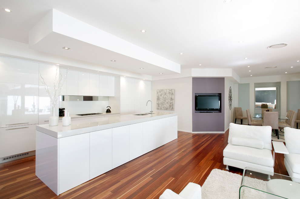Modern galley eat-in kitchen in Sydney with a drop-in sink, flat-panel cabinets, white cabinets, quartz benchtops, white splashback, glass tile splashback, stainless steel appliances, medium hardwood floors and with island.