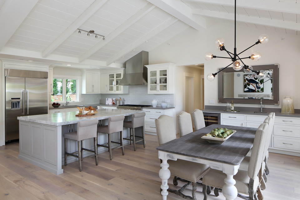 This is an example of a mid-sized traditional l-shaped open plan kitchen in San Francisco with a single-bowl sink, beaded inset cabinets, white cabinets, white splashback, ceramic splashback, stainless steel appliances, light hardwood floors, with island, quartzite benchtops and beige floor.