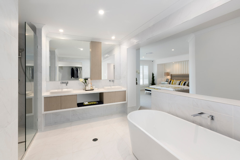 This is an example of a contemporary bathroom in Brisbane with light wood cabinets, a freestanding tub and engineered quartz benchtops.