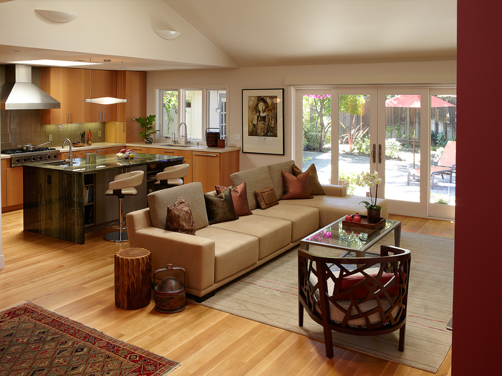 This is an example of a mid-sized contemporary open concept living room in San Francisco with orange floor, beige walls, light hardwood floors, no fireplace and a wall-mounted tv.