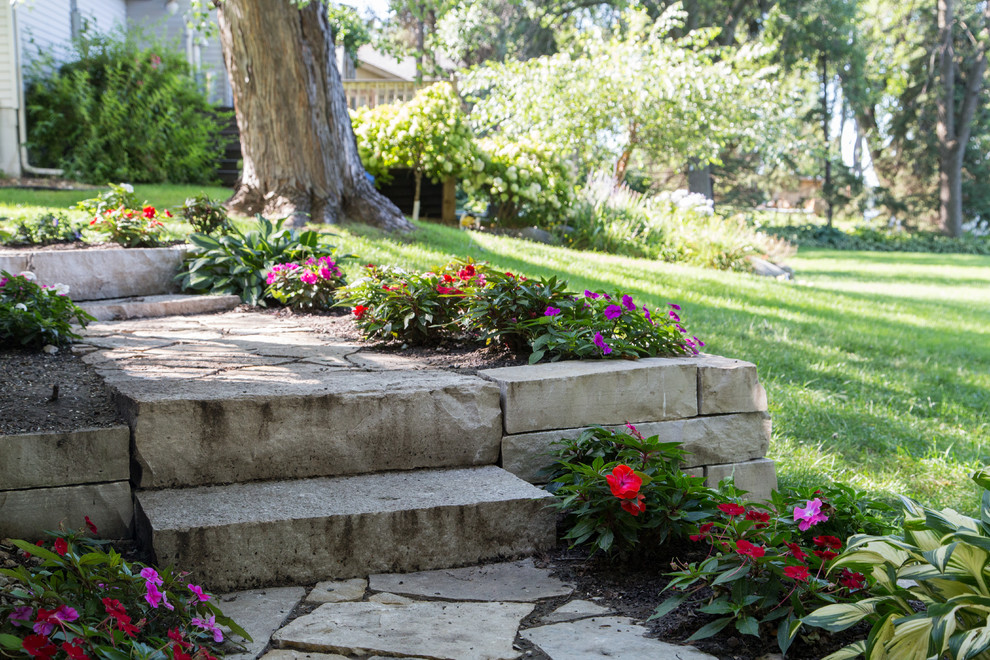 Design ideas for a small backyard garden in Minneapolis with a retaining wall and natural stone pavers.